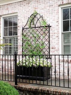 a planter with flowers in it is on the side of a fence near a brick building