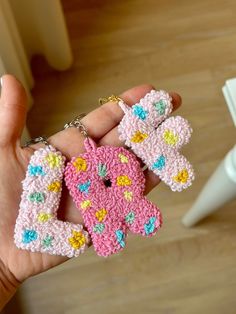 a hand holding three crocheted key chains