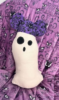 a stuffed ghost with a purple hat on it's head