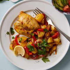 a white plate topped with chicken and veggies next to a bowl of vegetables