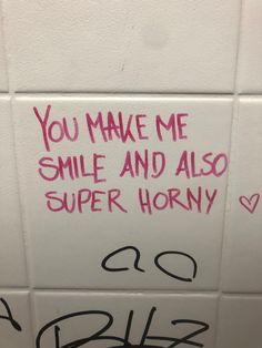 a bathroom wall with graffiti written on it