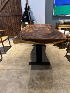 a wooden table sitting in the middle of a room with chairs around it and a painting on the wall behind it