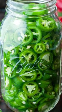 a jar filled with green peppers sitting on top of a table