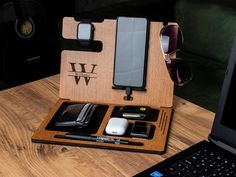 an open laptop computer sitting on top of a wooden desk next to sunglasses and other items