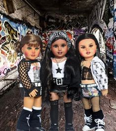 three dolls standing next to each other in front of graffiti covered walls and doorways