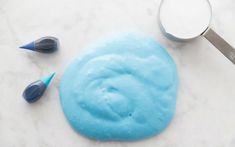 a blue cake sitting on top of a white counter next to a measuring cup and spatula