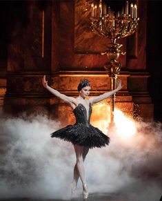 the ballerina is dressed in black and has her arms spread out as she stands on stage