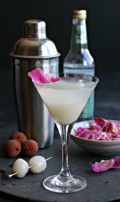 a drink in a martini glass with rose petals on the rim