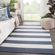 a blue and white striped rug in a living room with a couch, coffee table and potted plant