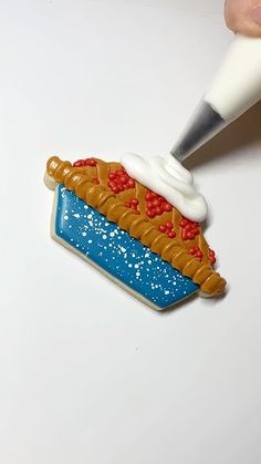 a cookie shaped like a hot dog being decorated with icing