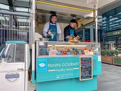 two people standing in front of a food truck