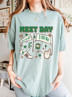 a woman wearing a t - shirt that says met day and has various symbols on it