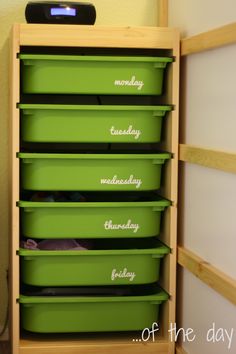 green bins are stacked on top of each other in the corner of a room