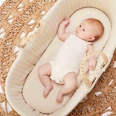 a baby laying in a crib on top of a wicker table next to a basket