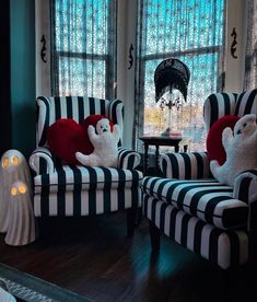 two striped chairs with ghost pillows on them in front of large windows and halloween decorations