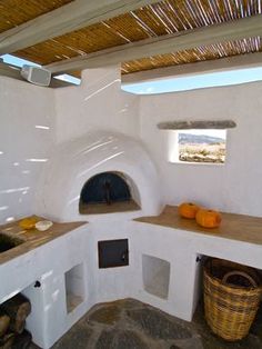 an outdoor kitchen with white walls and wood flooring, built into the side of a building