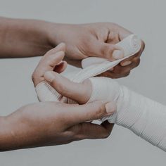 two hands with bandages on their fingers and one hand holding an arm cast over the other