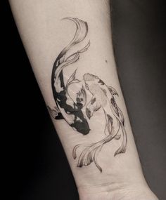 a black and white koi fish tattoo on the wrist