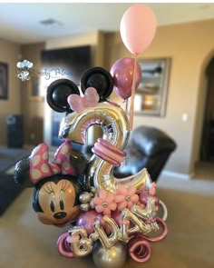 a mickey mouse figurine with balloons in the shape of numbers and minnie mouse