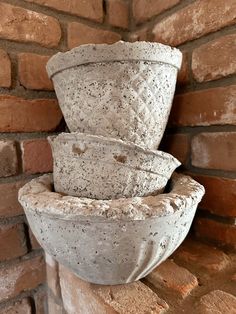 three cement pots are stacked on top of each other in front of a brick wall