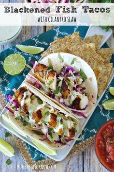 two tacos and chips on a plate with lime wedges