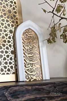 an intricately designed arch stands next to a vase with flowers in it on a shelf