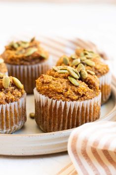 three muffins on a plate with pumpkin seeds