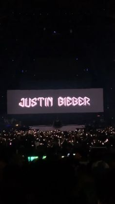 the words'just in bigger'are projected on a large screen at an event