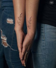 two people holding hands with tattoos on them