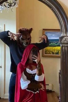 a man in a costume taking a selfie with a woman dressed as a devil