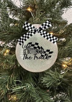 a christmas ornament hanging on a tree with the words life is better at the track