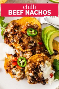 a white plate topped with chili beef nachos next to an avocado