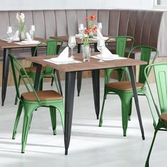 an empty restaurant table with green chairs and white napkins on the table next to it