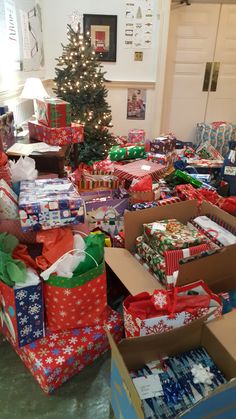 many wrapped presents under a christmas tree in a room filled with other boxes and gifts