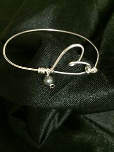 Silver Plated Twisted Wire Heart Bangle Bracelet With Black Fresh Water Pearl. The bracelet can also be made with a white freshwater pearl. Please select your pearl color upon check out. The silver plated wire is tarnish-resistant and nickel free making it great for sensitive skin. This bracelet measures 8 inches. One can be made in your size. Please select a bracelet size upon check out. A special gift for a loved one! Silver Heart-shaped Pearl Bracelet For Gift, Adjustable Pearl Heart Bracelet, Silver Heart-shaped Pearl Jewelry, Silver Heart-shaped Jewelry With Pearl Charm, Adjustable Pearl Bracelets With Heart Charm, Adjustable Heart Bracelet With Pearl Charm, Silver Bangle Bracelet With Pearl Charm, Silver Bracelet With Pearl Charm, Pearl Heart Beads Bracelet