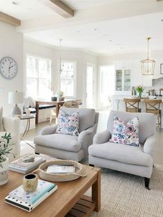 a living room filled with furniture and a clock on the wall above it's windows