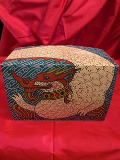 an artisticly designed box sitting on top of a red cloth