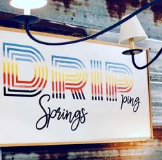 a sign hanging from the side of a building that says drip springs ping pong