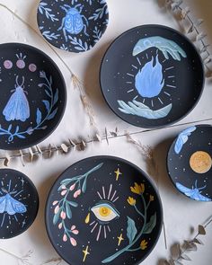 four black plates with painted designs on them