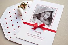 a christmas card with a red ribbon on it and a bell ornament next to it