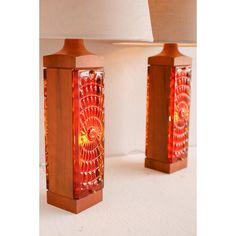 two red lamps sitting on top of a table next to a white lamphade