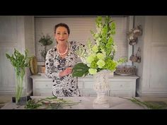 a woman standing in front of two vases with flowers on top of a table