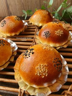 four buns with sesame seeds on them sitting on top of a wicker basket