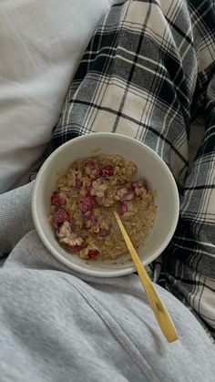 a bowl of oatmeal with strawberries in it and a wooden spoon