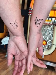 two people are holding hands with tattoos on their arms and one has a butterfly tattoo on the wrist