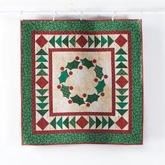 a green and red quilt hanging on a wall