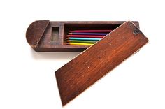 a wooden box filled with colored pencils on top of a white surface