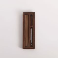 a knife and some chopsticks in a wooden box on a wall with white background