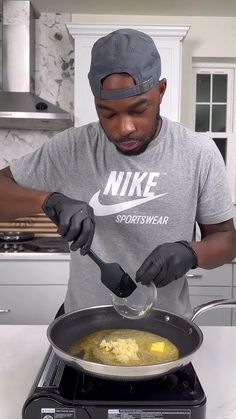 a man cooking food in a frying pan on top of an oven with a spoon