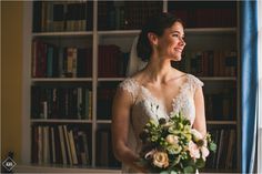 a woman standing in front of a book shelf holding a bouquet